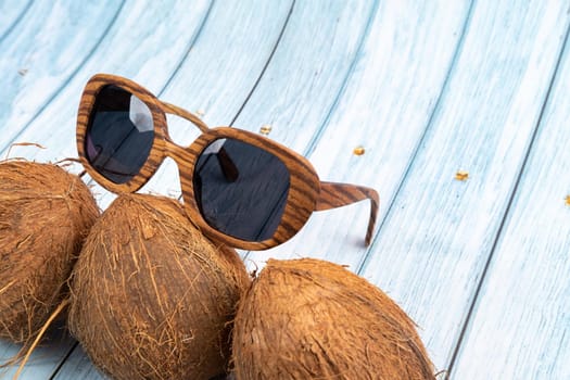 three whole coconuts and wooden glasses on a blue wooden background.