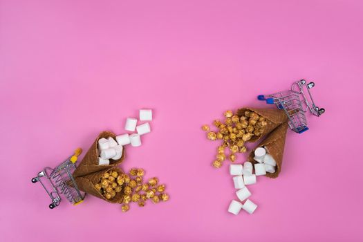 two shopping baskets with ice cream cones with sweets on a pink background.