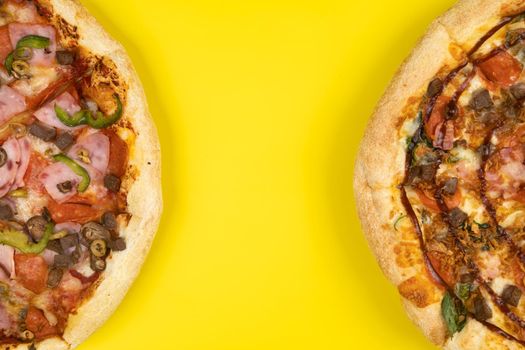 Two different Delicious big pizzas on a yellow background.