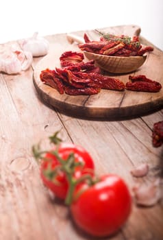 Mediterranean dried tomatoes garlic, thyme and fresh tomatoes on wooden table