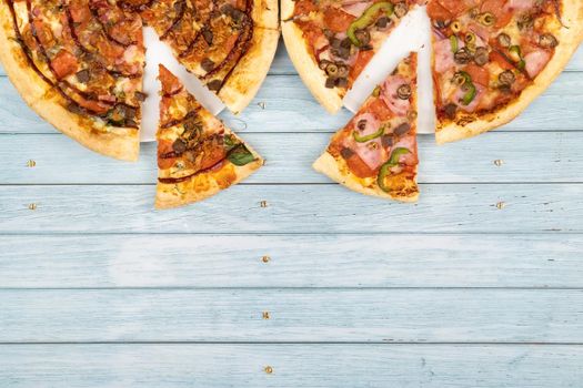 Two different delicious big pizzas on a blue wooden background.