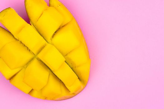 Fresh ripe mango on a pink background. Half a sliced mango on a pink background.