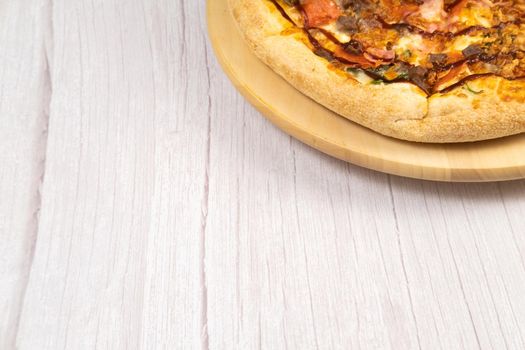 Delicious large pizza with bacon and spinach on a light wooden background.