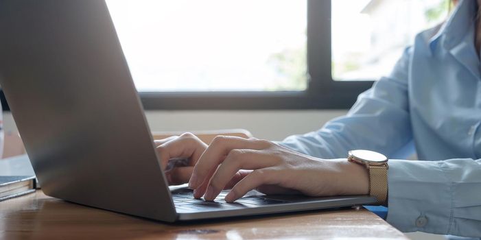 Close up of woman or accountant hand holding pencil working on calculator to calculate financial data report, accountancy document and laptop computer at office, business concept.