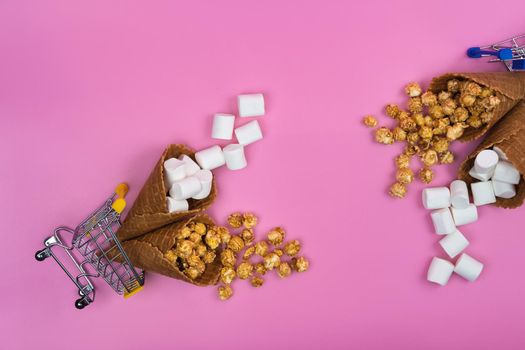 two shopping baskets with ice cream cones with sweets on a pink background.