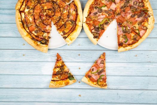 Two different delicious big pizzas on a blue wooden background.