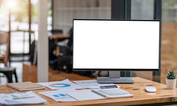 Close up view of simple workspace with open blank screen laptop, frame and notebook on white table with blurred office room background.