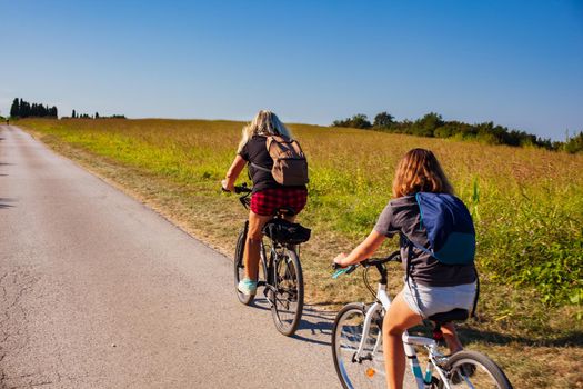 Mother and daughter cyclists riding in the countryside track of Strunjan, Slovenia