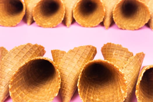 Empty waffle cones for ice cream on a pink background.