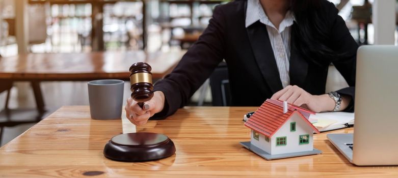 Real Estate Law concept. Gavel on sounding block in hand's female judge at a courtroom, working for the insurance compensations. report the case on table in modern office..