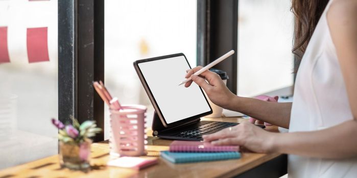 Asian woman hand holding pen stylus writing on digital tablet computer.