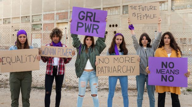 Group of multiracial feminism activist protesting for woman's rights and empowerment holding signs. Panoramic banner image. Equality concept.