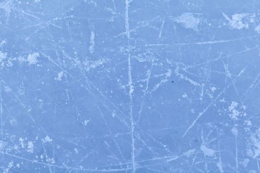 Empty ice rink with skate marks after the session outdoor. skating ice rink texture covered with snow in daylight. Close up of blue ice rink floor, copy space