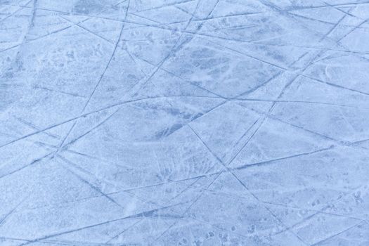 Empty ice rink with skate marks after the session outdoor. skating ice rink texture covered with snow in daylight. Close up of blue ice rink floor, copy space