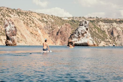 Side view foto of a man swiming and relaxing on the sup board. Sportive man in the sea on the Stand Up Paddle Board SUP. The concept of an active and healthy life in harmony with nature