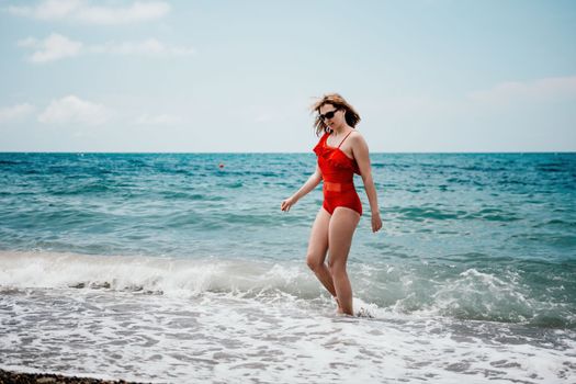 Young happy woman walks carefree on the seaside. Happy lady in red bikini. Portrait beautiful young woman relax smile around beach sea ocean in holiday vacation travel trip.