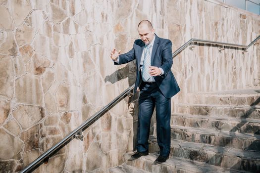 Portrait of a senior professional man in a suit with various problems. A middle-aged businessman with a briefcase descends the stairs.