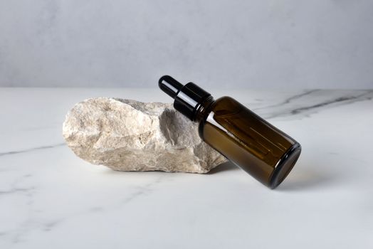 Bottle with a pipette with a cosmetic product for body skin care on a stone. Selective focus.