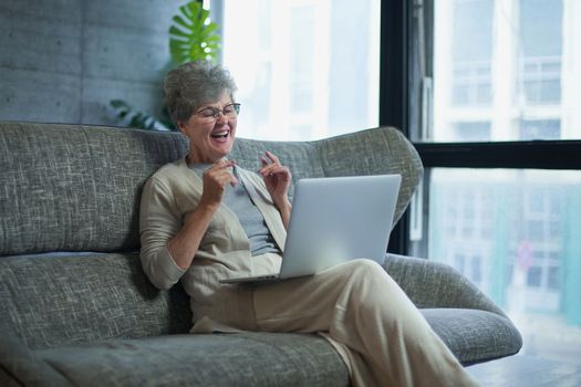 Woman using laptop while sitting on sofa in living room at home