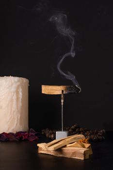 zen image of smoking palo santo,, holy stick with candles and japa-mala on black background