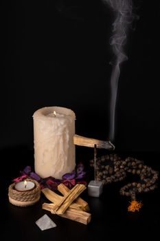 zen image of smoking palo santo,, holy stick with candles and japa-mala on black background