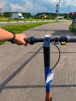 Electric scooter riding. Electric scooter on the road, woman's hand on the steering wheel of the scooter.