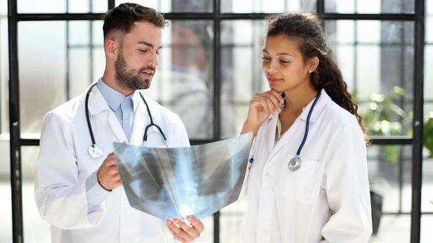 Two busy doctors working with papers and x-rays in hospital lobby