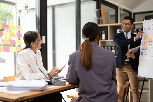 Business adviser explaining business plan strategy on flipchart to colleagues, male coach or adviser giving presentation at briefing, reporting about results or growing sales.