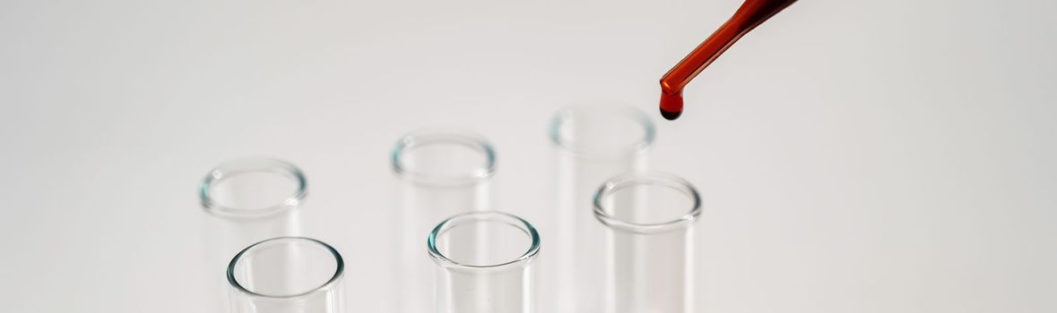 Close-up of a laboratory assistant dripping blood from a pipette into a test tube on a white background