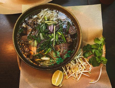 Soup Pho Bo in a bowl on a table in a restaurant.