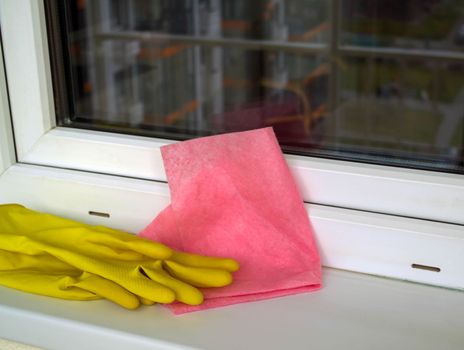 Window washing. In the photo, rubber gloves, a rag lie on the windowsill.