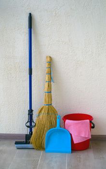 House cleaning. In the photo there is a red bucket, a broom with a dustpan and a mop.