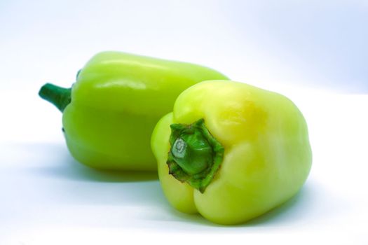 Two green peppers on a white background close-up.