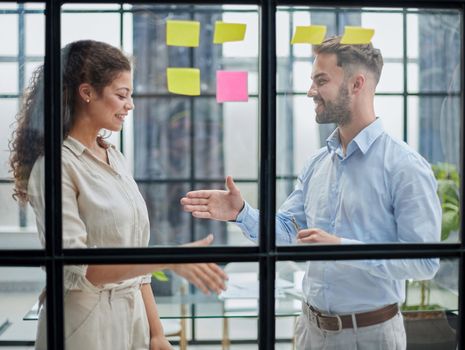 Business people talking in the hallway of the modern office building with employees working behind glass partitions. Work in a large business corporation