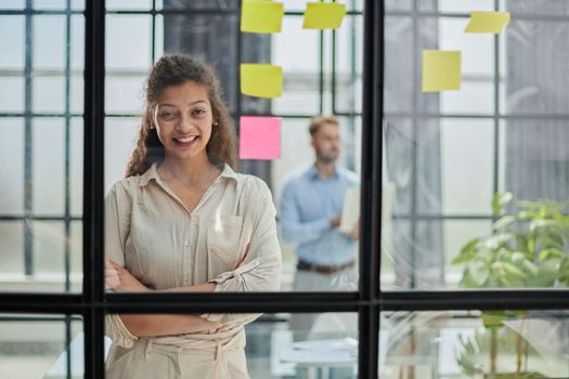 Bringing her vision to life. Shot of a confident businesswoman presenting an idea to her colleague using adhesive notes on a glass wall in the office.