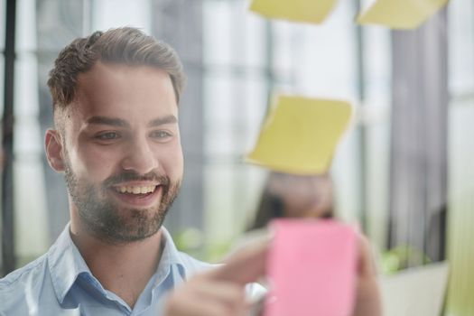 businessman is working on a project. Business man pointing at a note on the glass wall