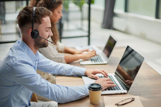 Handsome male customer service agent working in call center office as a telemarketer.