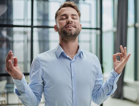 Young businessman relaxing while standing in the office