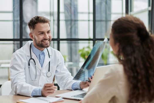 Young serious competent male doctor looking at X-ray at doctor's office