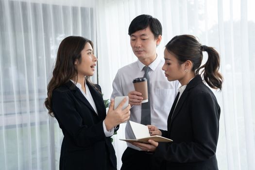 Mentor, manager with coffee advice younger colleagues in workplace. Businesspeople discussing or planning financial project strategy, talking together for harmony and strong teamwork in office concept