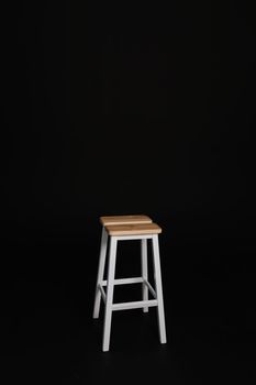 minimalistic wooden chair against black background. Concept modern interior and design furniture in room. High stool in loft style. Retro Bar chair. Vintage wooden metal chair