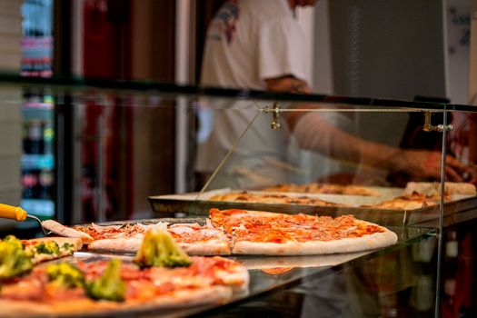 Large pizza cut into slices on the counter, italian street style.