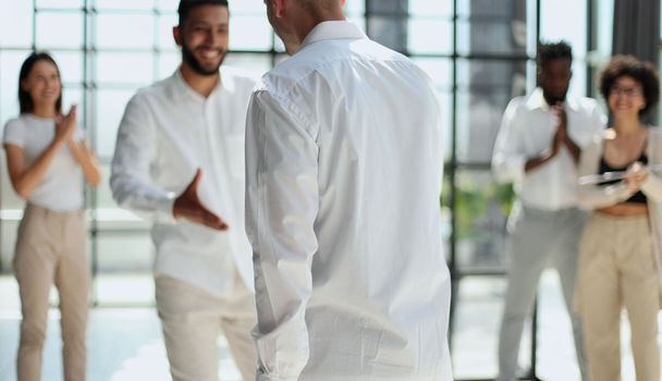 Glad to work with you. Young modern men in smart casual wear shaking hands and smiling while working in the creative office