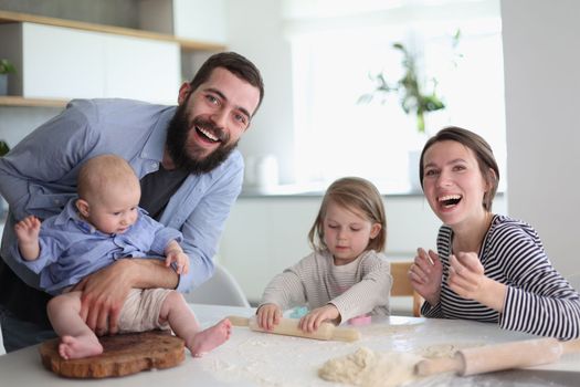 Happy parents playing with their children in the kitchen