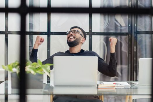 Business man sitting at his desk in the office with a laptop