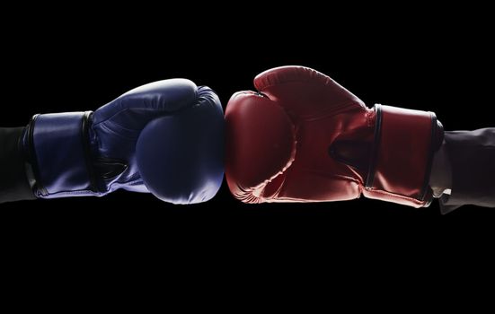 Two men's hands in boxing gloves. The concept of confrontation. Photo on a black background