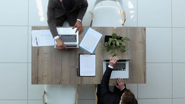 two businessmen sitting on a chair and watching something on a laptop