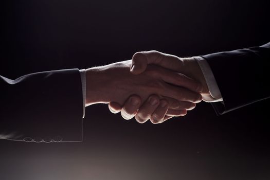 Photo of two men shaking hands on a black background