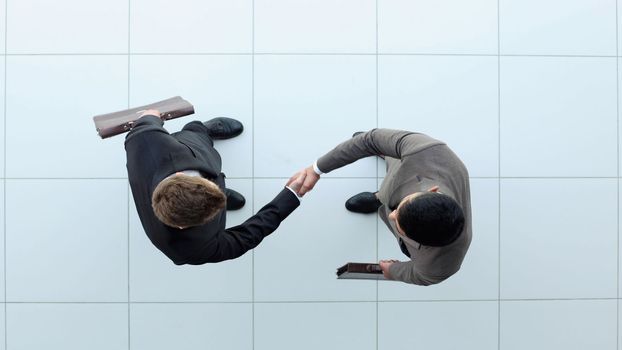 Two businessmen shake hands. view from above