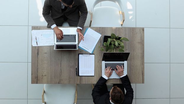 two businessmen sitting on a chair and watching something on a laptop